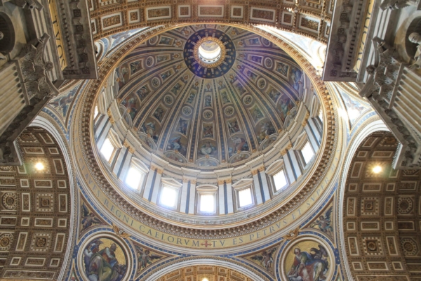 Vista desde abajo de la cúpula dorada y pintada de la basílica de San Pedro, con la luz que entra por sus ventanas