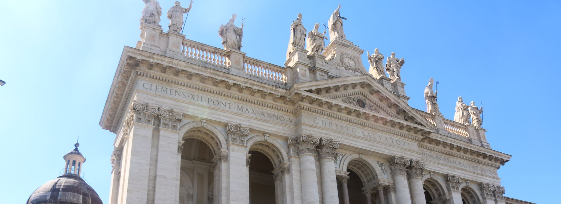 Façade of the Archbasilica of St John Lateran, Rome, with its statues of Christ and the saints against a blue sky