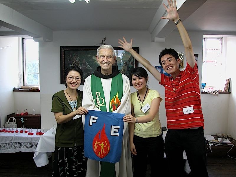 A priest and participants smiling and holding a FIRES flame banner at an Encounter in Nagoya